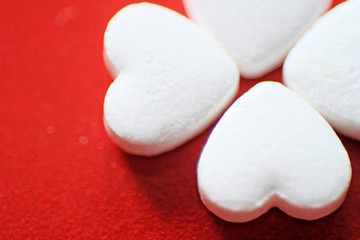 Obraz na płótnie Canvas Heart-shaped pills on a red background. Red felt background. Heart disease medications. Close up.