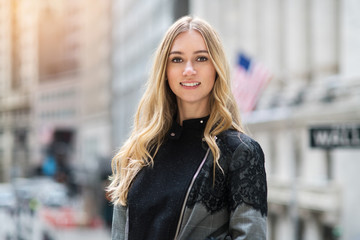 Fototapeta premium Beautiful young adult smiling businesswoman portrait in New York City Wall Street