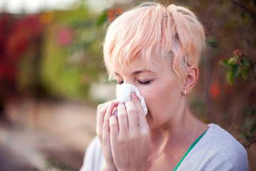 Woman with with allergy symptom blowing nose. People, health care and medical concept