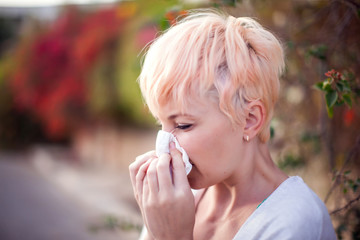 Woman with with allergy symptom blowing nose. People, health care and medical concept
