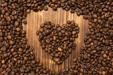 Roasted coffee beans in the form of heart wooden background