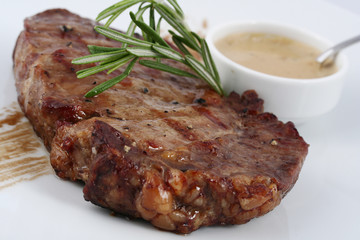 Appetizer steak medium rare with rosemary leaves and sauce close up on a white background.