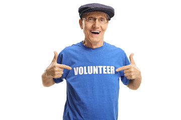 Cheerful elderly man wearing a volunteer signed t-shirt and pointing at it