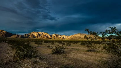 Poster Mountain range in the Mojave desert at dusk catches the last rays of golden light along route 66.  © buttbongo