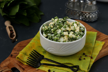 Salad with ramson wild garlic, eggs and mayonnaise in a white bowl