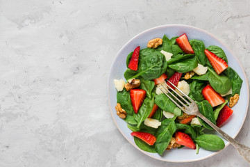 Fresh salad with strawberry, spinach leaves, parmesan cheese and walnuts. healthy keto diet food. top view