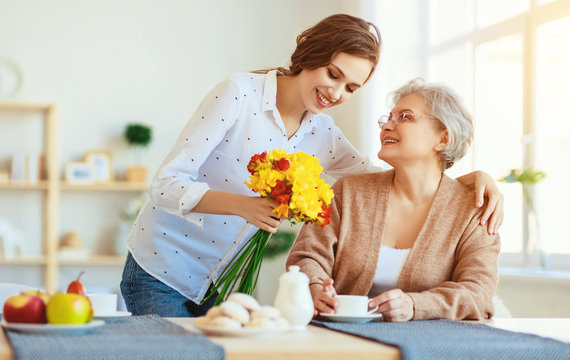 Happy mother's day! adult daughter gives flowers and congratulates an elderly mother on holiday .