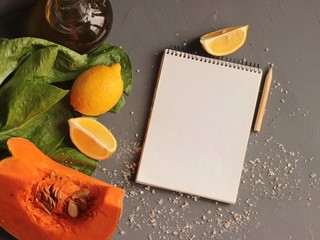 Pumpkin slice with seeds on a dark background. Lettuce leaves, lemons, bottle of olive oil and...