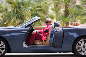 a rich businessman driving a cabriolet