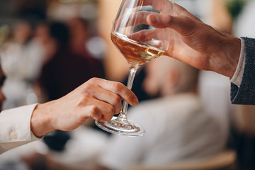 from hand to hand pass a beautiful glass of white wine at dinner in a restaurant
