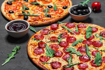 Pepperoni Pizza and Pizza with Mozzarella cheese, Tomatoes, pepper, olive, Spices and Fresh arugula. Pizza Margherita or Margarita on Dark grey black slate background