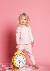 Lovely blonde toddler playing with alarm clock