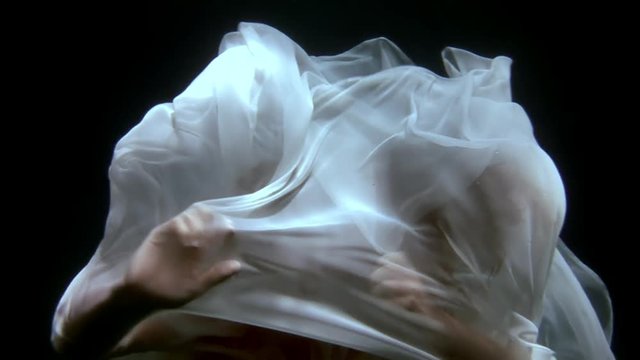 Underwater model freediver swims in white cloth. Young woman freediver under water of sea. Creativity and art of creating images on background of clear transparent blue water.