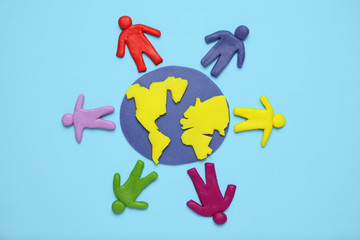 Plasticine figurines of people of different races are on planet earth. A variety of interactions, communication and globalization. Cartoon art.