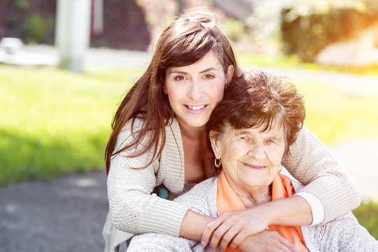Seniorin im Rollstuhl mit netter Pflegerin im Park 