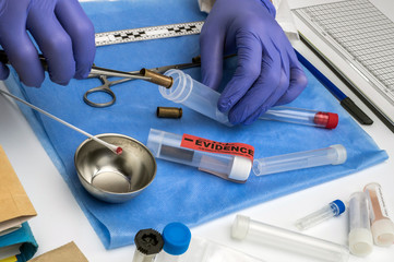 Scientific police picking up bullet cap with tweezers, conceptual image, horizontal composition