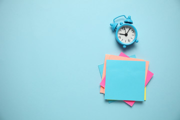 Blue alarm clock and a reminder note. Time management concept. Copy space for text.