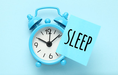 Blue alarm clock and paper reminder - sleep.