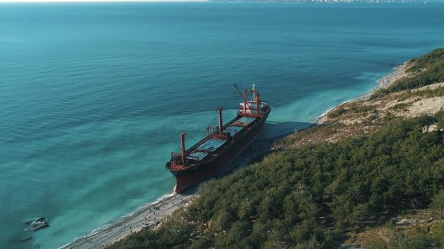 Aerial view of large cargo ship in still blue water near coastline. Shot. Sea transportations