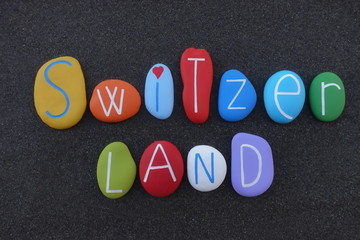 Switzerland country name composed with multi colored stones over black volcanic sand