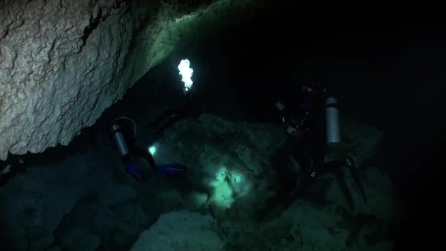 Divers in cave in underground water of underwater Yucatan Mexico cenotes. Dangerous extreme diving in clean and clear water.