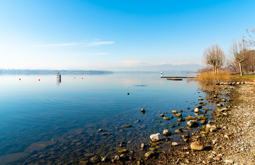 Landscape of Lake Varese in a clear winter day, with mountains with snow covered peaks in background. Italy