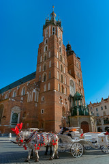 Naklejka na ściany i meble Horse carriage at Market square and St. Mary's Basilica in Krakow, Poland in summer sun light