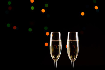 glasses of champagne on black  background with bokeh circles. Place for text.
