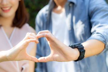 Closeup of happy couple fun making gesture heart shape with hand outdoor together, man and woman with relation feeling love with symbol and sign, lover and romantic concept.