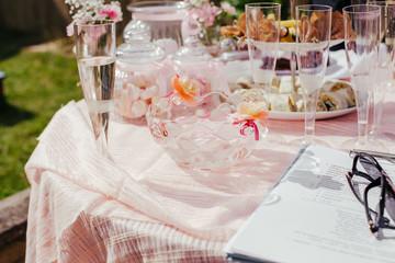 Candy table, sweets in the glass jars, pink decor on table outside in the summer. Party table with food, canapes, snacks. Planning party, notebook and glasses.