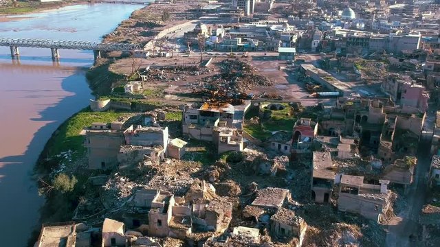 Drone down to up aerial tilt of the Tigris river and Mosul city after the military operation against ISIL.