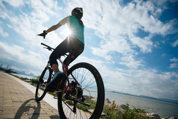 Fototapeta na wymiar Hands free cycling female riding mountain bike on seaside