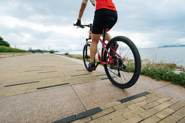 Woman cyclist riding Mountain Bike on sunrise seaside