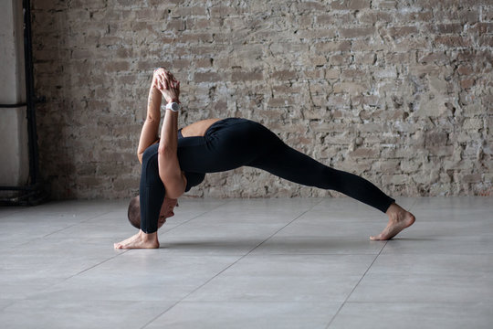young woman in sportswear doing yoga stretching exercise - high lunge with twist on stone floor