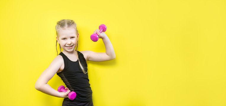 Theme sport and health. Beautiful caucasian child girl with pigtails posing on yellow background with smile. little athlete holding pink dumbbells. Banner for advertising, space for text copy space