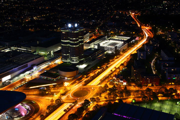Fototapeta na wymiar Modern European aerial night cityscape with broad circle road intersection, commercial, office and industrial buildings in outskirts illuminated by street and car light, Munchen Bayern Germany Europe