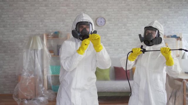 cleaning service workers or scientists in protective overalls dancing