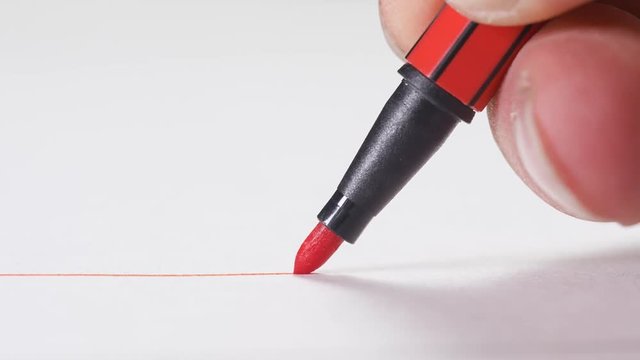 Orange marker tracing a line on a white piece of paper. macro shot.