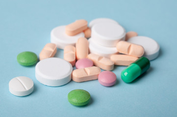various pills, tablets and capsule of medicine on blue background; medical care and safe drug use concept