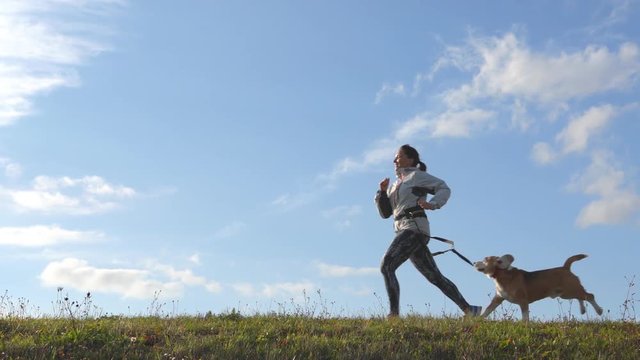 Slow-motion footage of woman running with beagle on clear day