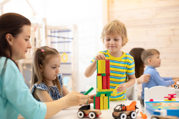 Educational toys for preschool and kindergarten children. Cute little kids playing with blocks in daycare center.
