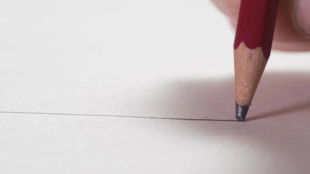 Wooden pencil tracing a line on a white piece of paper. macro shot.