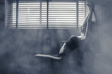 portrait of female having sexy posing in dark room with light ray and smoke effect