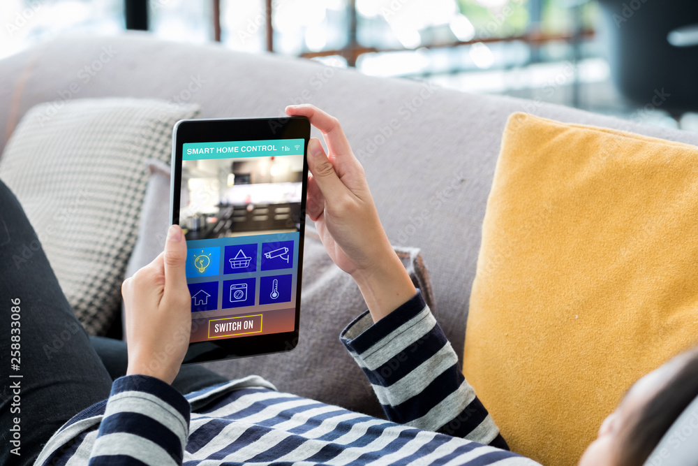 Aufkleber smart home automation control concpet.woman lying down on sofa using tablet control device in home.d