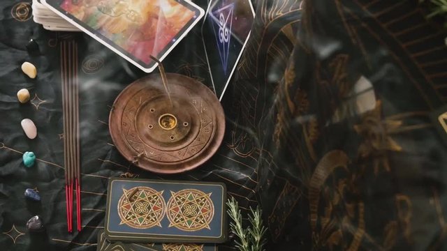 Focus shift from incense to altar with tarot cards