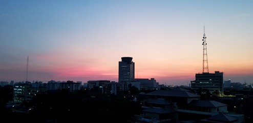 Silhouette of high building, village and telecommunication tower at sunset or sunrise time - City life, Exterior structure and Dawn or New day concept