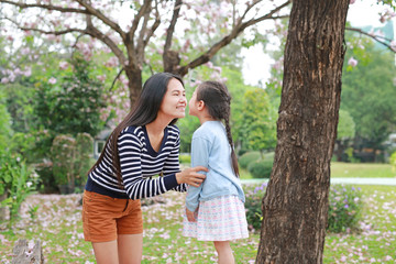 Cheerful mother and her daughter in garden with fully fall pink flower around outdoor.