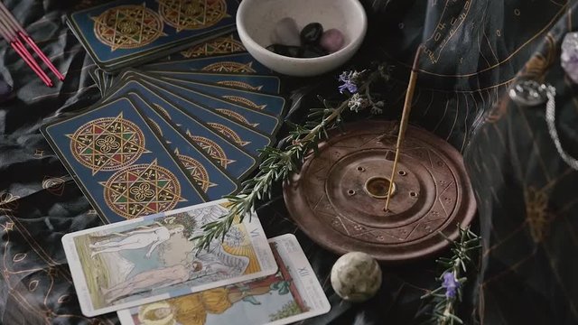 Slow zoom out of altar with crystals, tarot, incense and rosemary