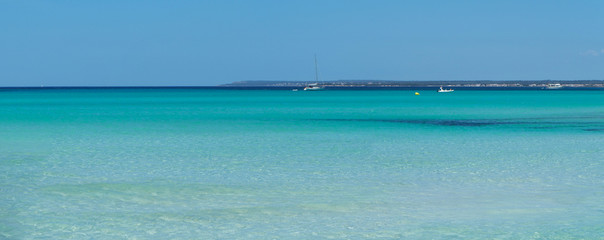 Fototapeta na wymiar Colonia Sant Jordi, Ses Salines, Spain. Amazing view of the boats with a turquoise sea close to the charming beach of Es Trencs. It has earned the reputation of Caribbean beach of Mallorca