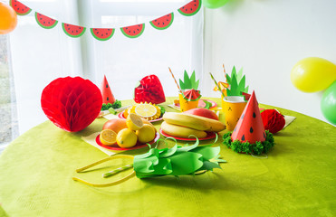 Decor for a holiday of children's birthday. Fruit party. Cake and sweet candy. Disposable tableware and tropical fruits.